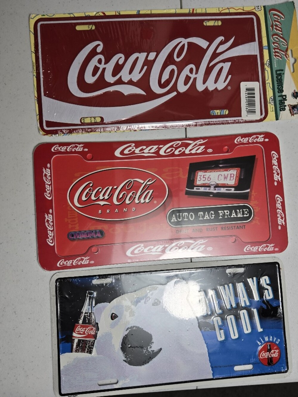 3 Coke License Plates. 1 Coke License Plate Frame. All New Original Packaging